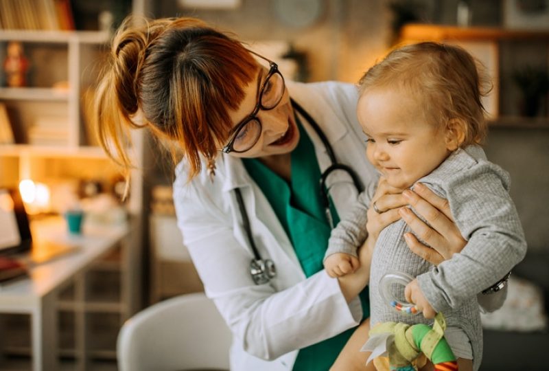 Female doctor playing with baby boy on the table in doctors office