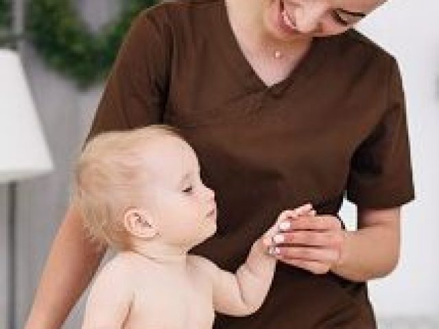 A little funny baby having massage with professional female masseuse. Children's massage on the couch in a modern cozy room. Kind and friendly children's doctor.